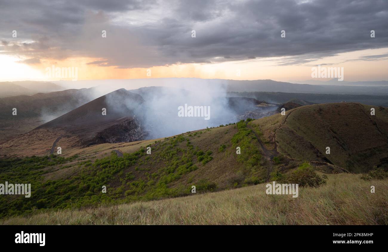 Paesaggio con vulcano attivo e fumo che si alza sullo sfondo del tramonto Foto Stock