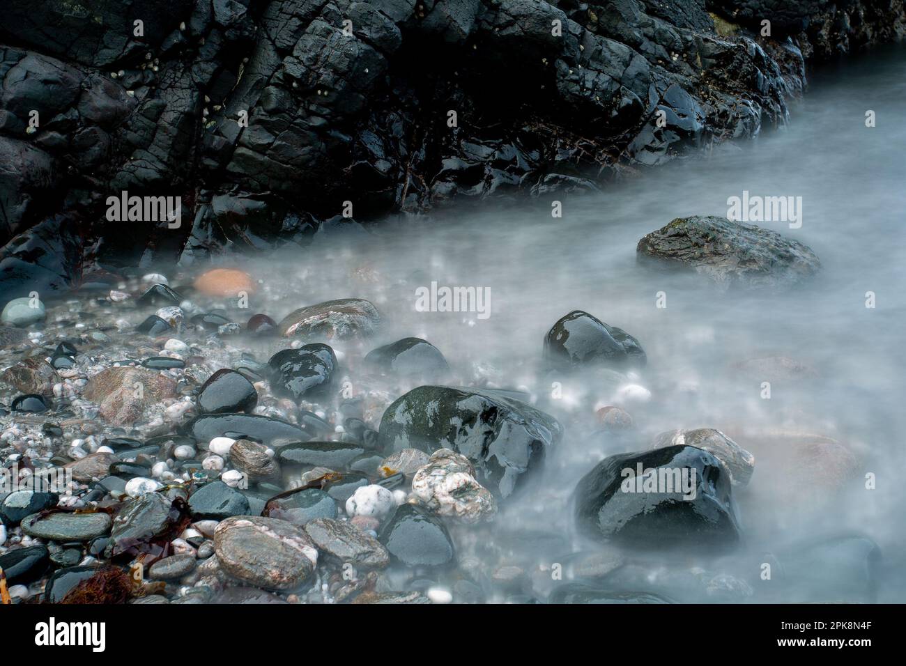 Primo piano di ciottoli in acqua a Antrim Coast, Northern Island Foto Stock