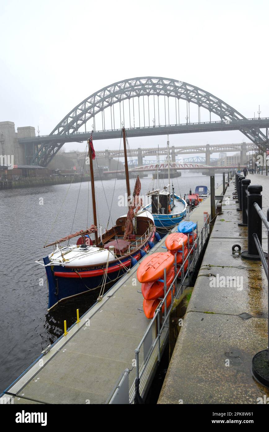 Newcastle upon Tyne, Tyne and Wear, Inghilterra, Regno Unito. Tyne Bridge (1928) sul fiume, in una giornata grigia e piovosa. Il Lifeboat di Tynemouth ormeggiato sul molo Foto Stock