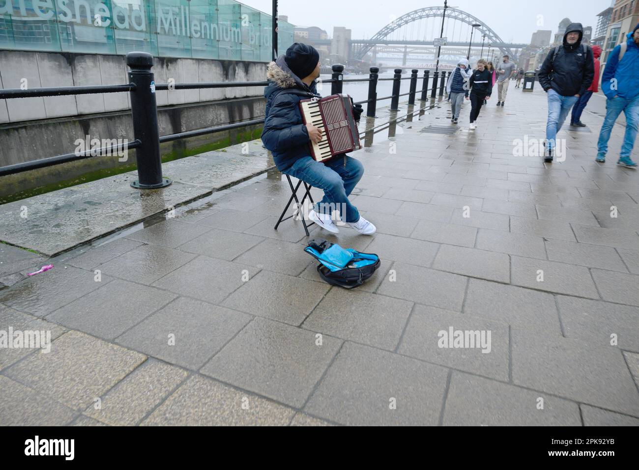 Newcastle upon Tyne, Tyne and Wear, Inghilterra, Regno Unito. Busker suona la fisarmonica sul Quayside vicino al Millennium Bridge Foto Stock