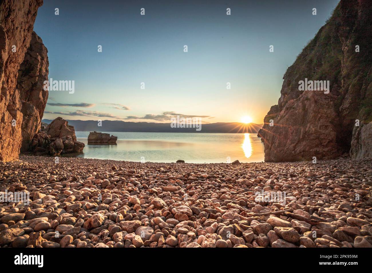 Spiaggia nascosta / Spiaggia segreta al porto di Vrbnik. bella piccola baia circondata da scogliere e con una spiaggia di pietra. Alba sul mare Adriatico, Isola di Krk, Croazia Foto Stock
