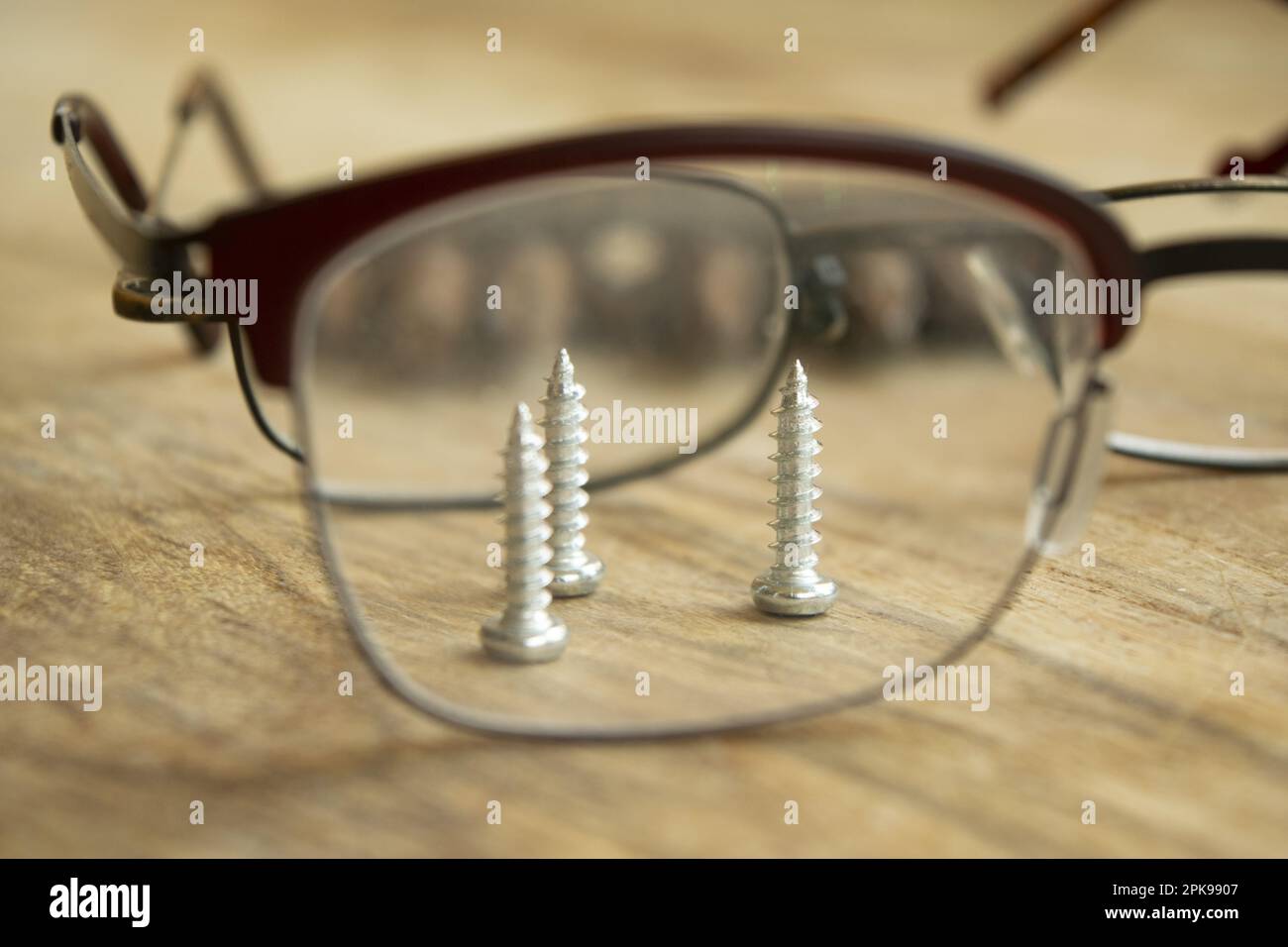 concetto di lavorazione manuale di precisione con viti visibili attraverso gli occhiali Foto Stock