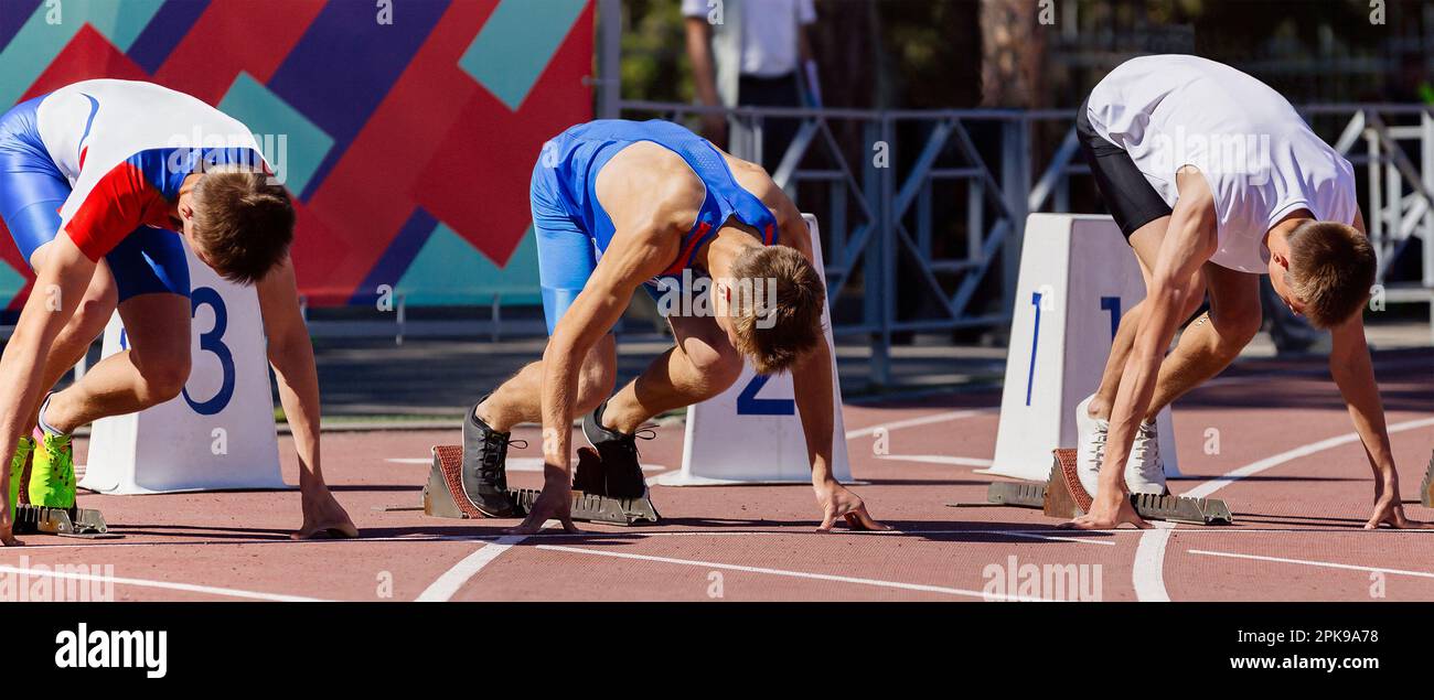 atleti maschi pronti a correre 100 metri in pista stadio, campionato di atletica estiva Foto Stock