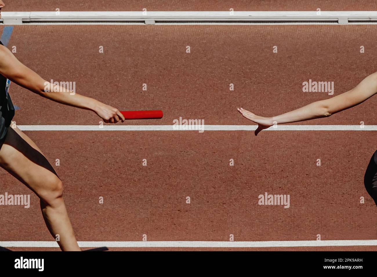 mano femmina runner che passa il baton in corsa relè gara in estate atletica concorrenza Foto Stock