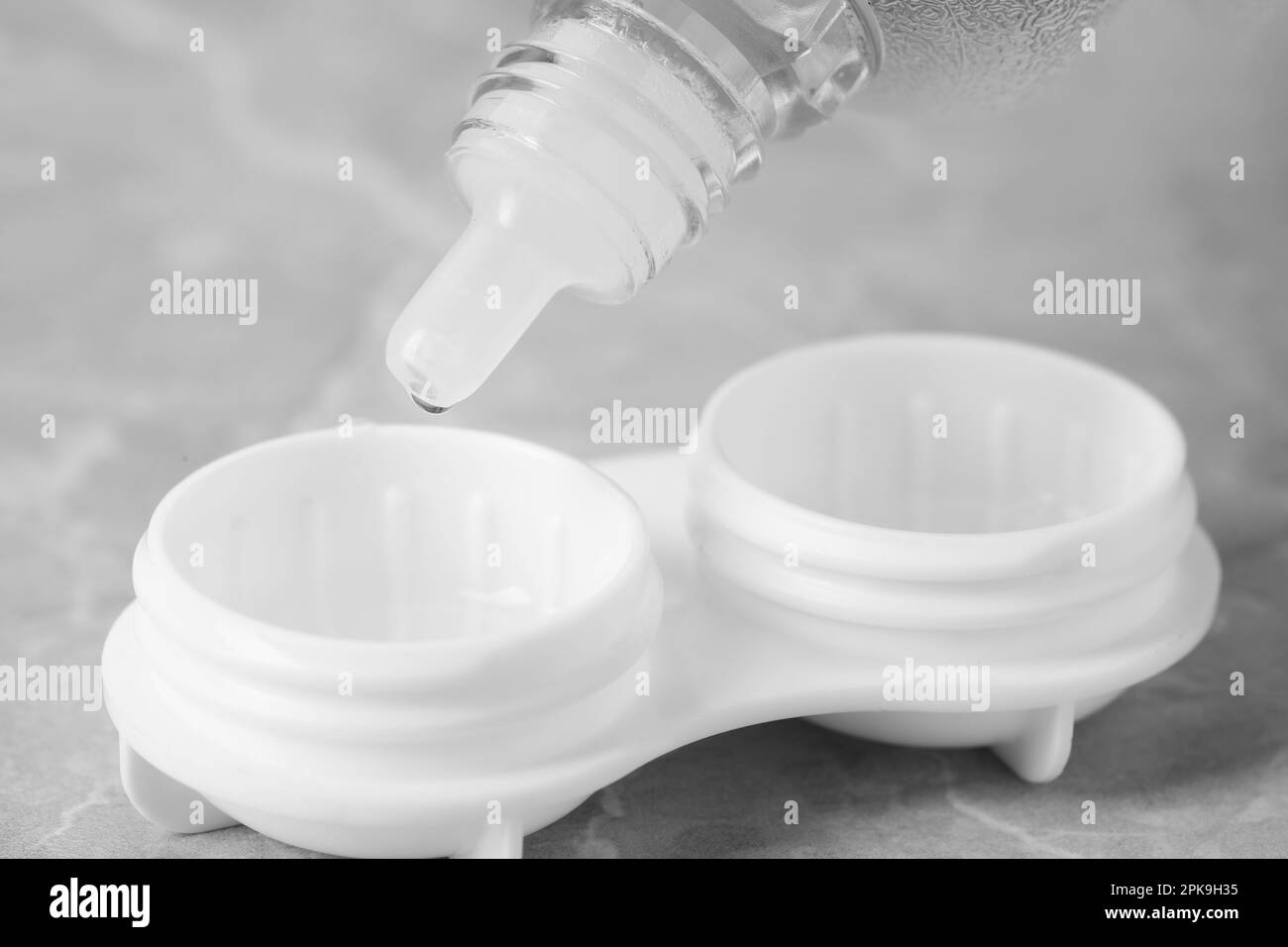 Soluzione gocciolante nella scatola con lenti a contatto su tavolo grigio chiaro, primo piano Foto Stock