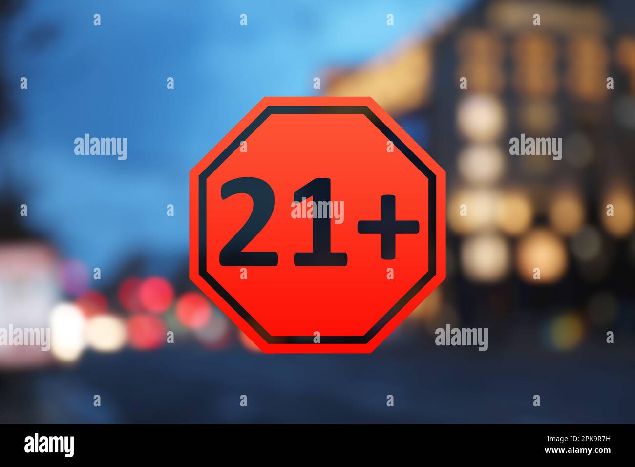Segno limite di età superiore a 21 anni e vista sfocata della città di sera Foto Stock
