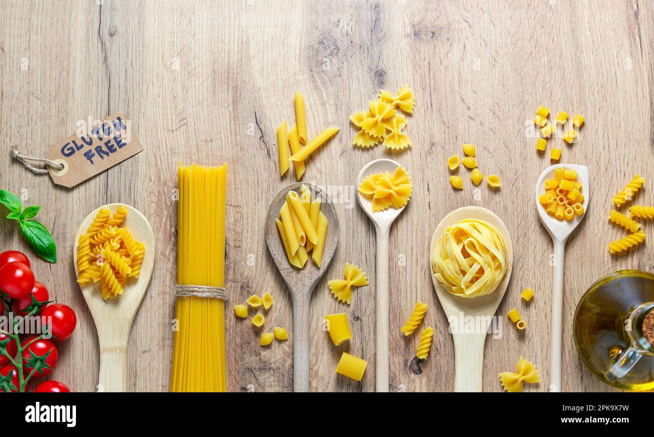 cucchiai di legno con diversi tipi di pasta, pomodoro, olio e senza glutine Foto Stock