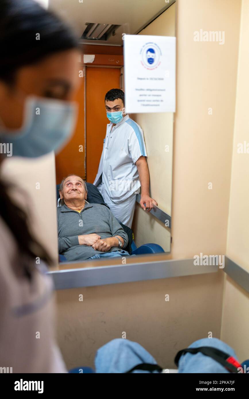 Due assistenti infermieri mettono un paziente disabili a letto nella sua stanza presso la casa di cura. Foto Stock