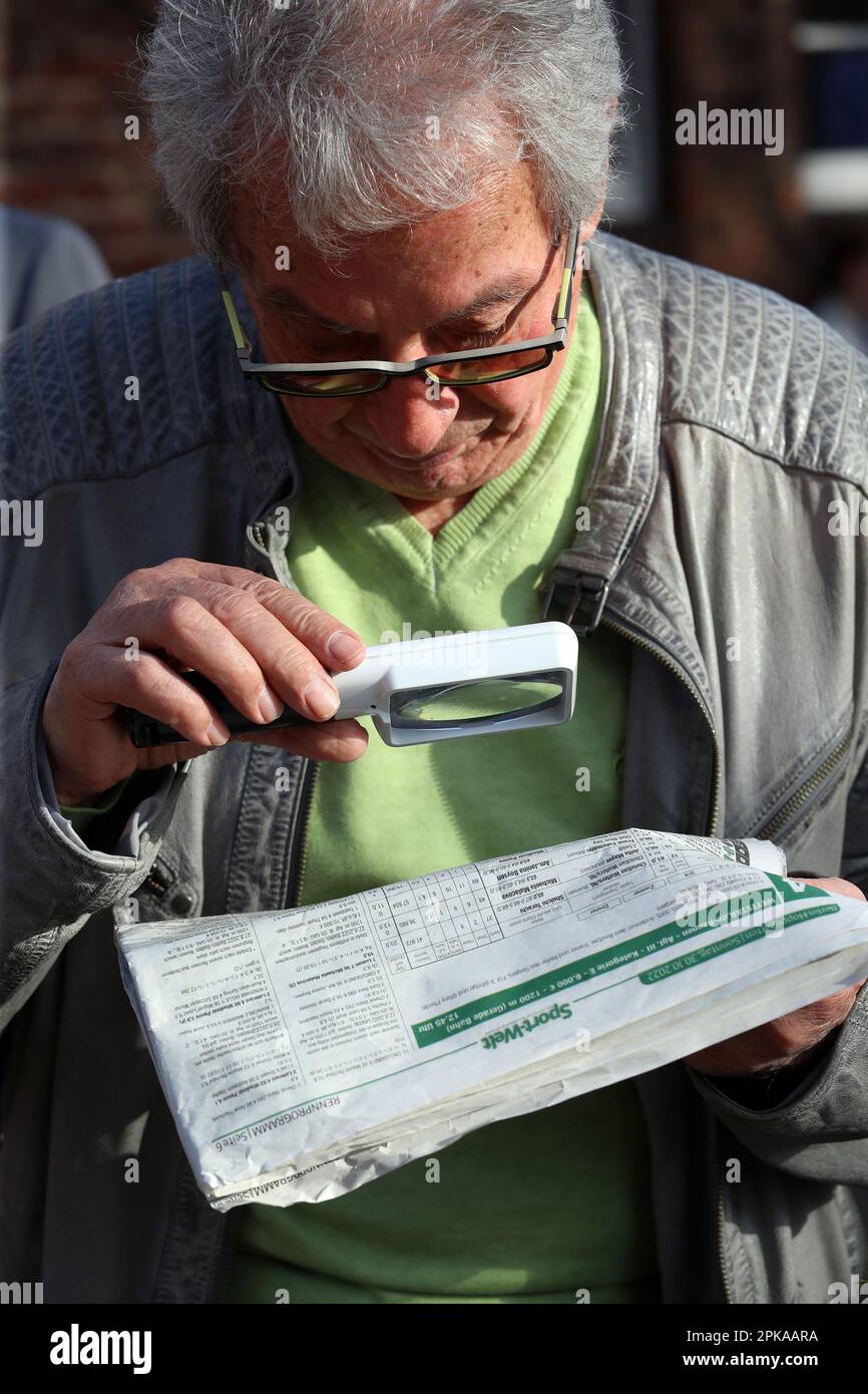 30.10.2022, Germania, Brandeburgo, Hoppegarten - uomo che legge un giornale con una lente d'ingrandimento. 00S221030D704CAROEX.JPG [VERSIONE DEL MODELLO: NO, PROPRIETÀ Foto Stock