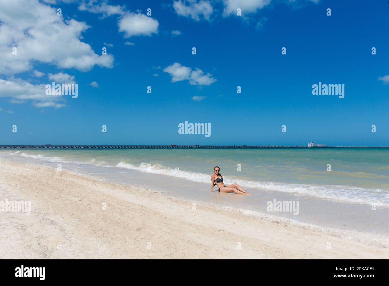 Bella giovane donna in posa su una spiaggia Progero Messico durante il giorno di sole. Spiaggia bianca con palme e cielo blu. Foto Stock