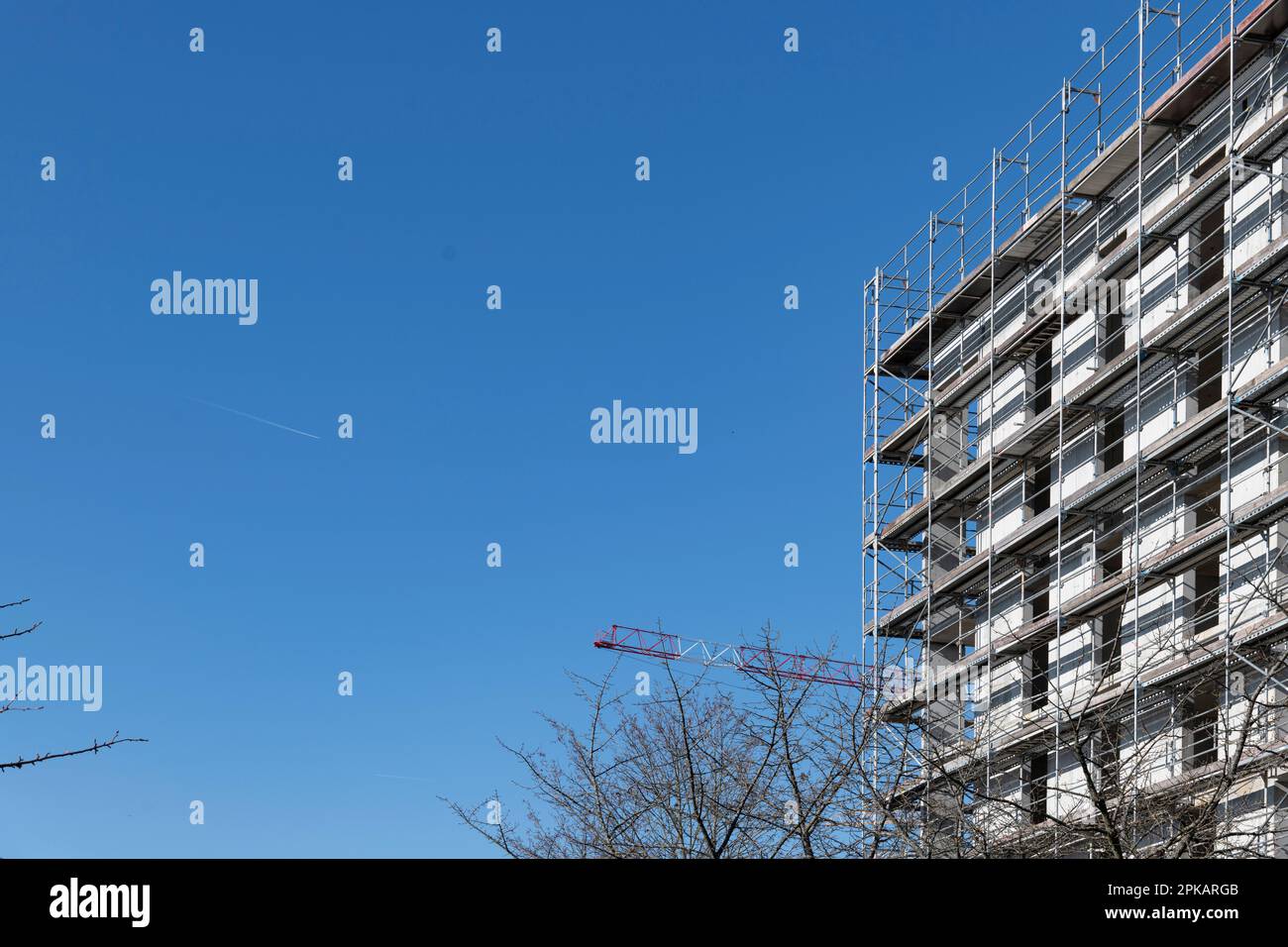 Edificio a piu' piani con ponteggi in conchiglia contro il cielo blu luminoso Foto Stock