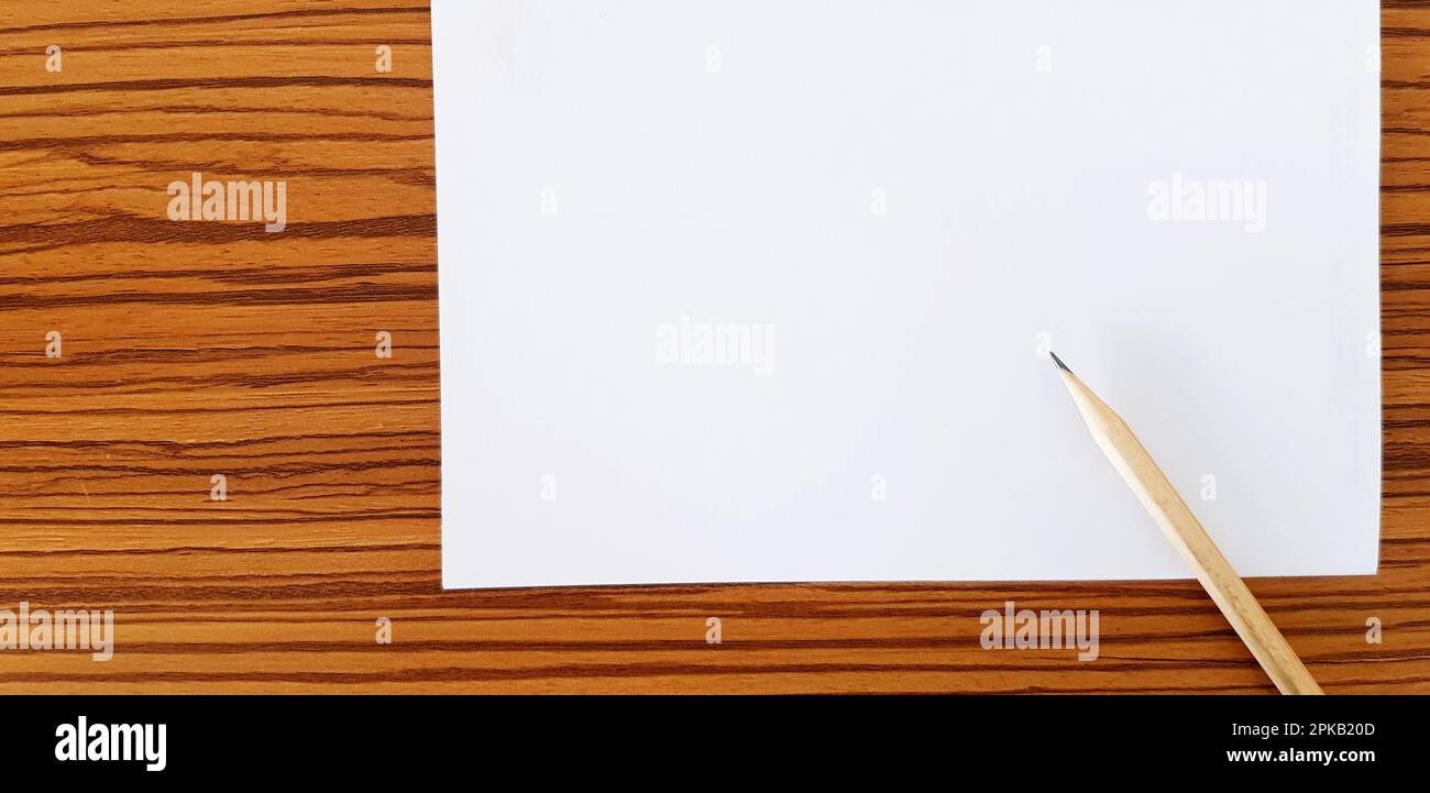 Matita marrone con carta bianca messa su tavolo di legno con spazio di copia per il testo di riempimento. Istruzione, documento e concetto di oggetto Foto Stock