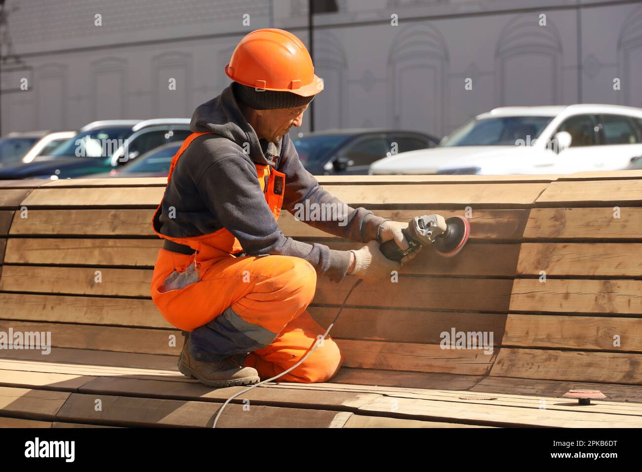 Operaio pulisce il banco di legno prima di dipingere. Miglioramento delle strade della città in primavera Foto Stock