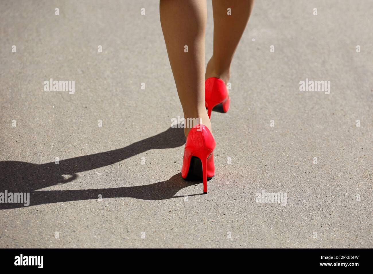 Gambe di donna snella in scarpe rosse su tacchi alti e calze che camminano lungo la strada. Moda femminile nella città di primavera Foto Stock