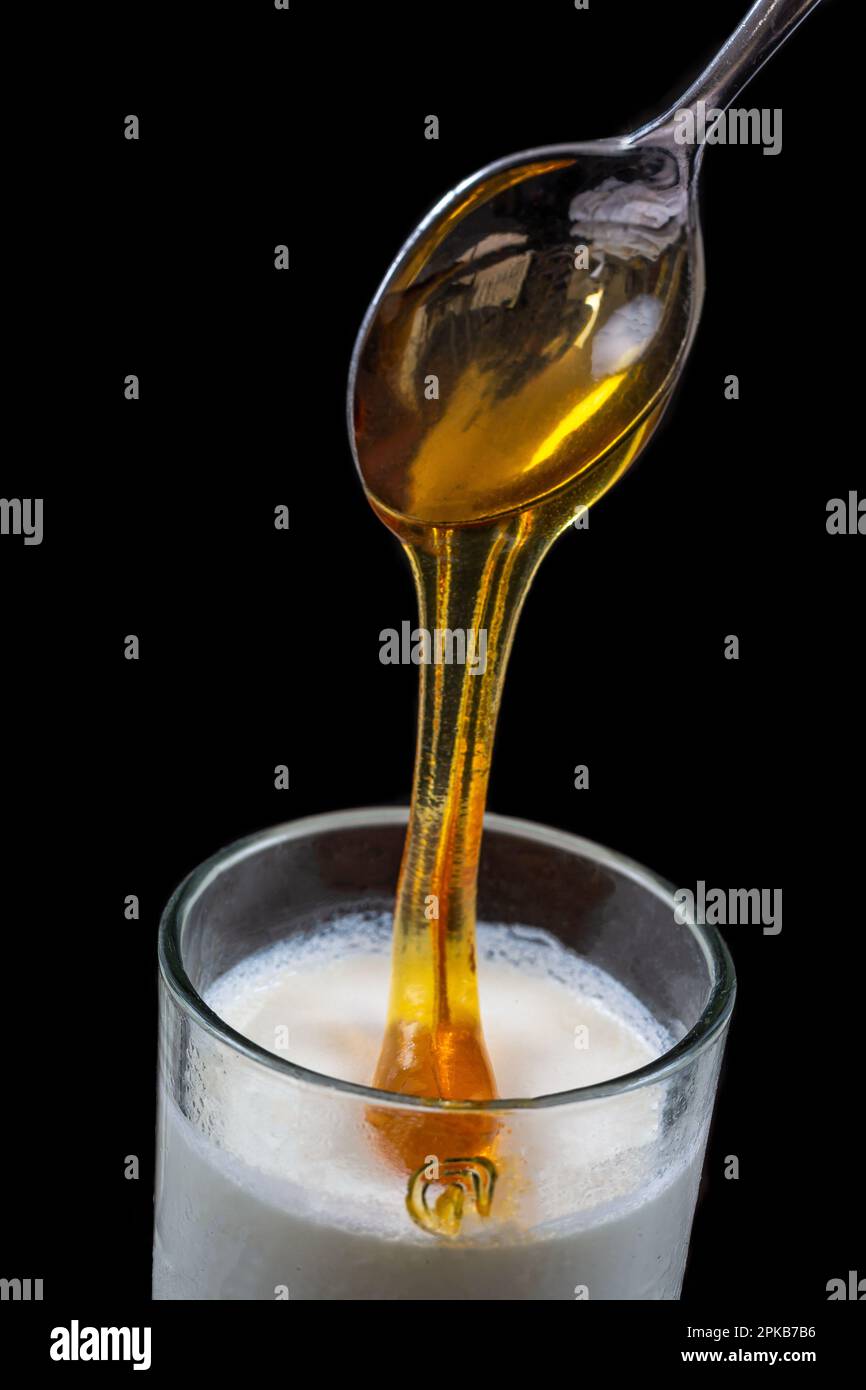 Miele che sgocciola da un cucchiaio sopra lo yogurt. Foto Stock