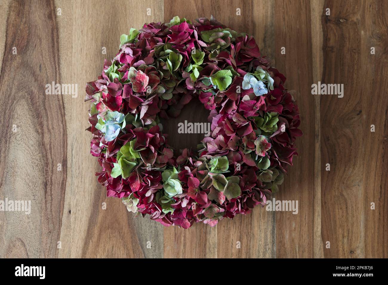 Corona floreale legata da fiori di idrangea rosso scuro, verde e azzurro, decorazione con materiali naturali Foto Stock