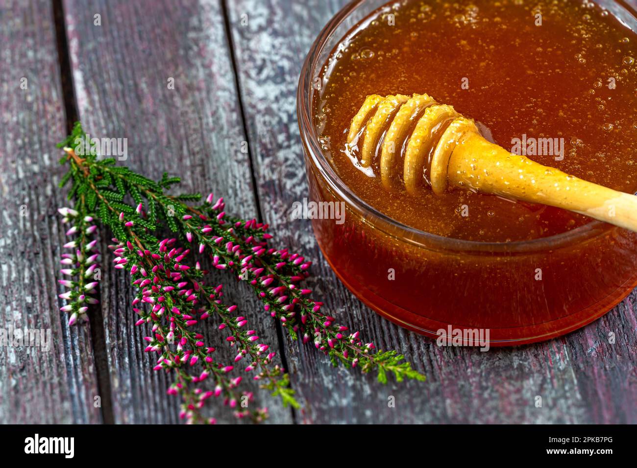 Un piattino pieno di miele di erica e un rametto di erica. Foto Stock