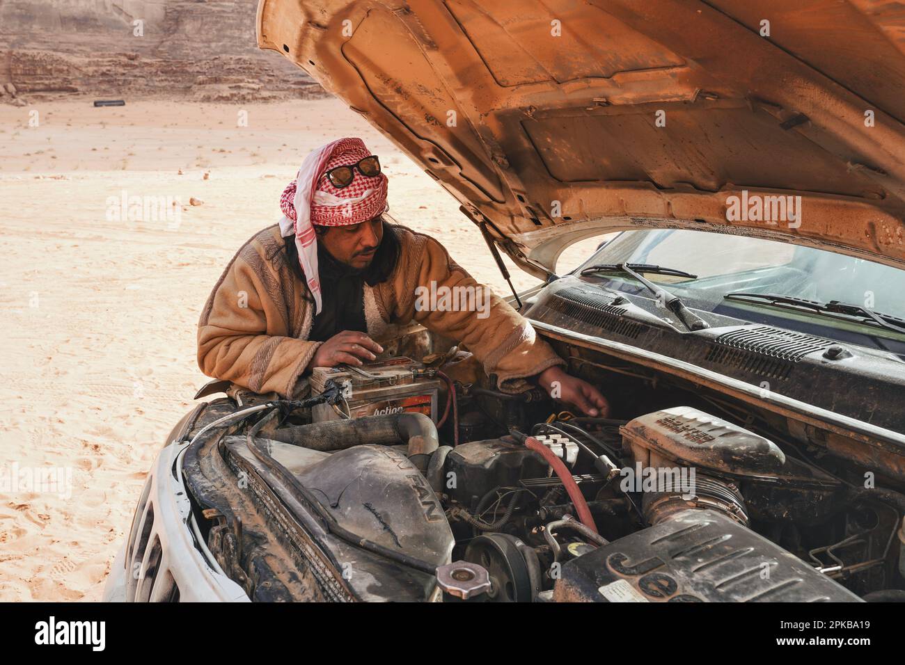 Wadi Rum, Giordania - 17 gennaio 2020: Guida turistica beduina sconosciuta e autista che indossa abiti tradizionali, controllando il motore del suo veicolo 4wd, d Foto Stock