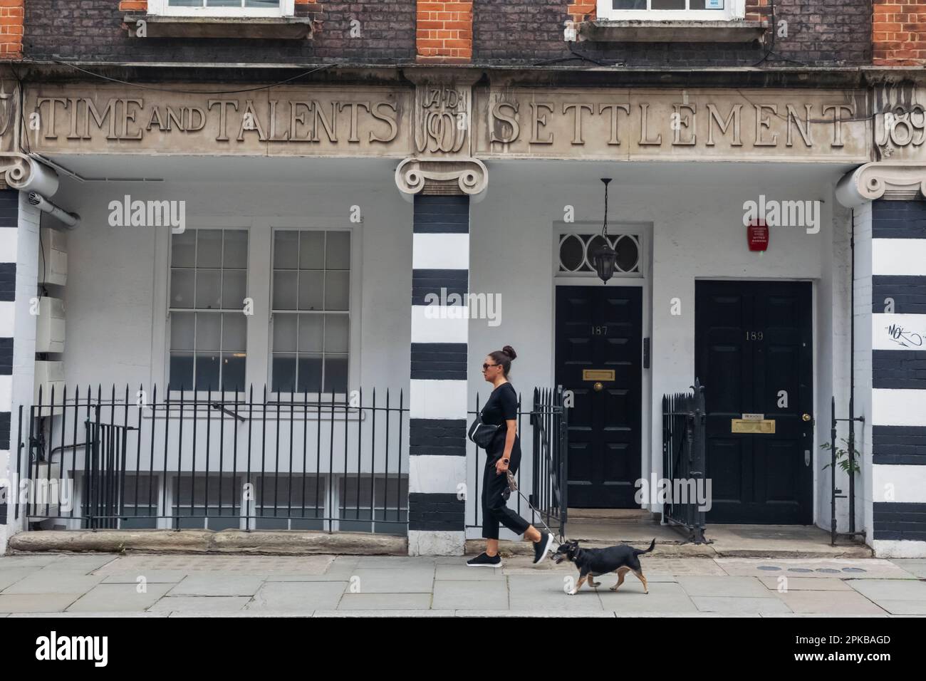 Inghilterra, Londra, Southwark, Bermondsey Street, Women Walking Dog di fronte all'edificio storico Foto Stock
