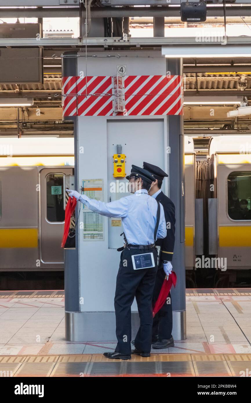 Giappone, Honshu, Tokyo, Stazione ferroviaria di Shinjuku, due guardie della piattaforma Foto Stock