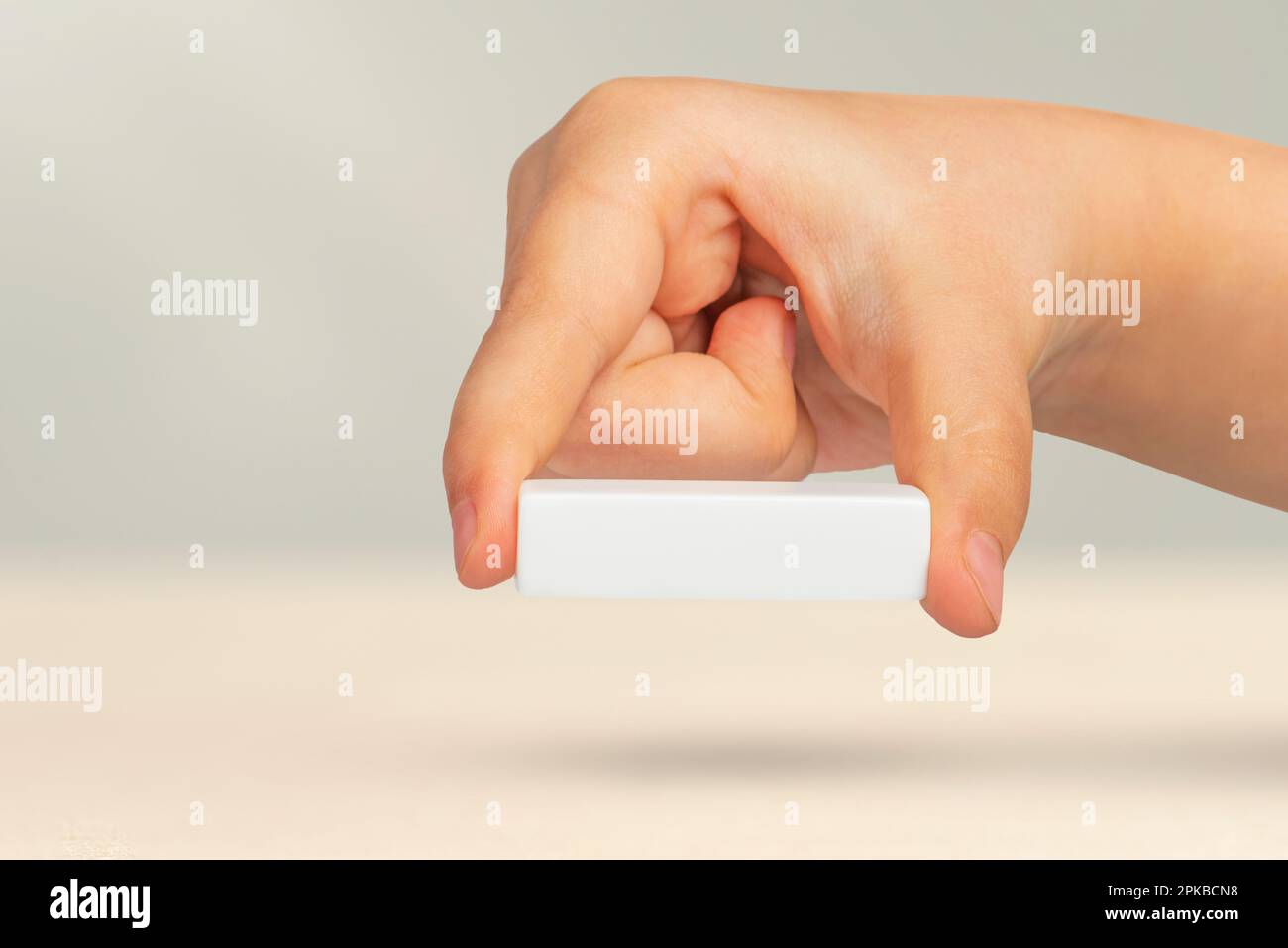 Segno meno in mano. Segno meno bianco nella mano di un bambino su uno sfondo grigio. Sottrazione o riduzione di qualcosa, rimozione, sottrazione o riduzione. Foto Stock