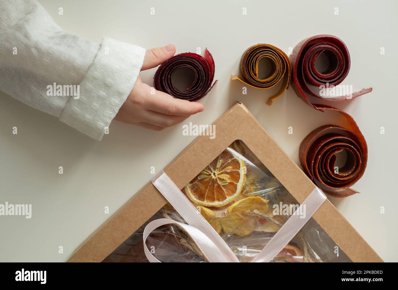 Il bambino prende i frutti canditi da un insieme con i frutti vari - i frutti canditi. Dessert in regalo. Foto Stock