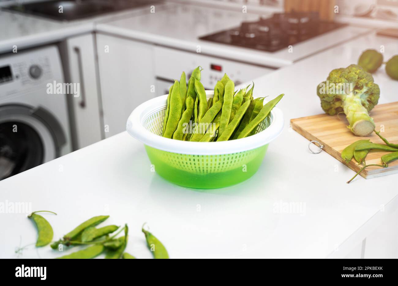 Moderno interno cucina con verdure verdi, fagioli romano helda, piselli verdi e broccoli sul tavolo. Cucina bianca luminosa. Il concetto di salute Foto Stock