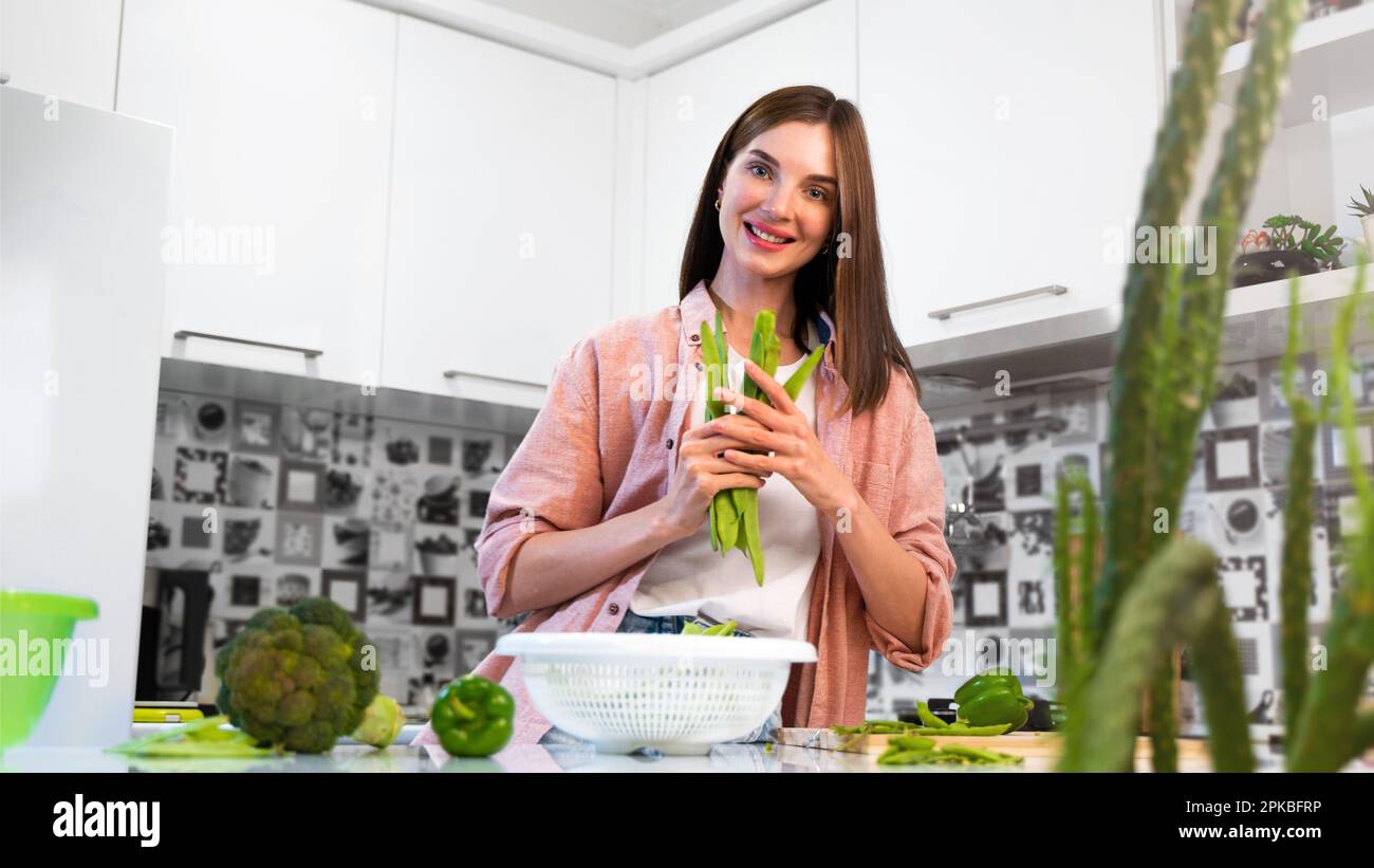 Una giovane donna sorridente che tiene in mano i fagioli verdi di romano helda. Il concetto di una nutrizione sana e dieta vegetariana. Stile di vita Foto Stock