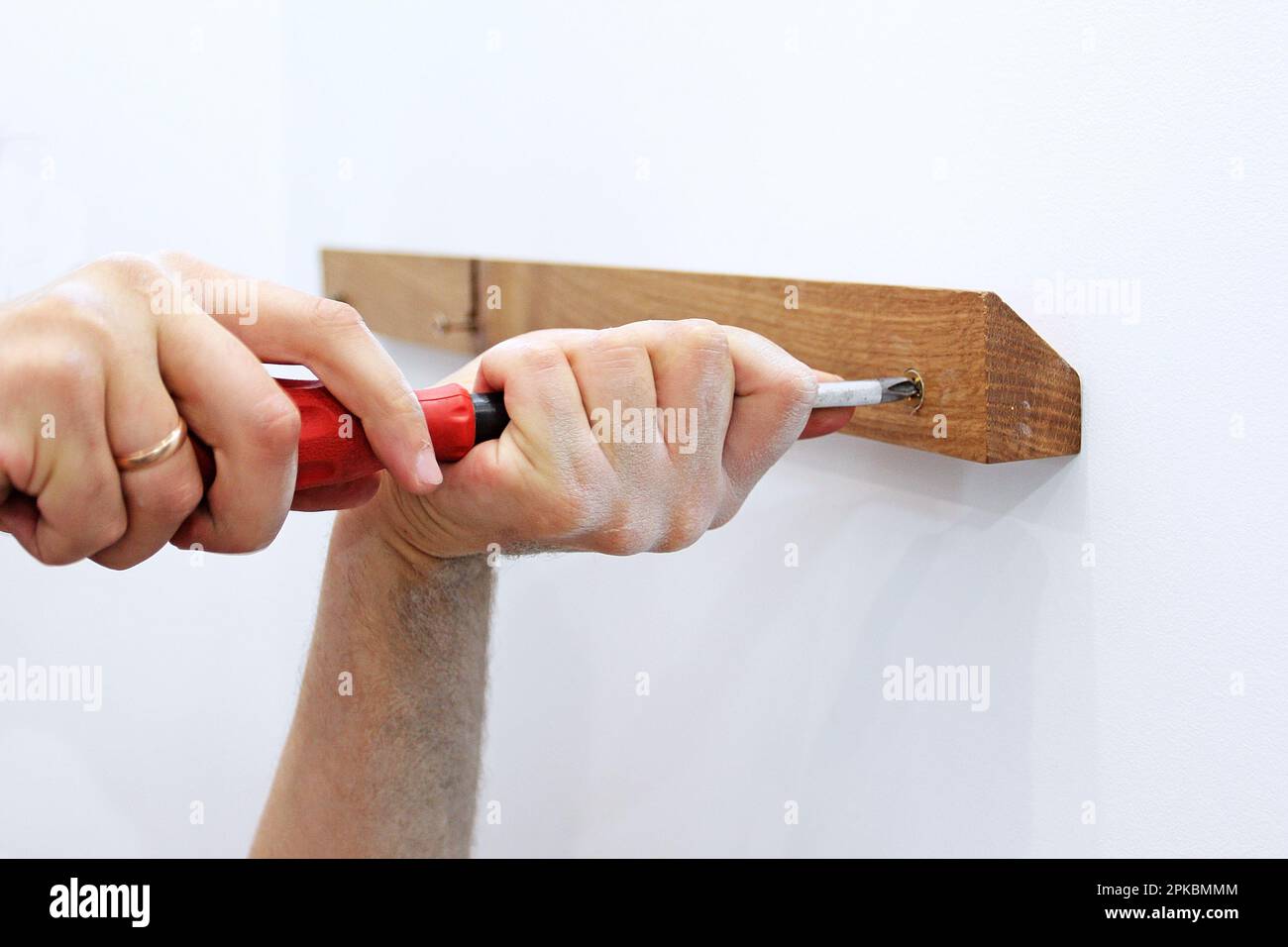 girare la vite dorata nella barra di quercia sulla parete bianca nel corridoio Foto Stock