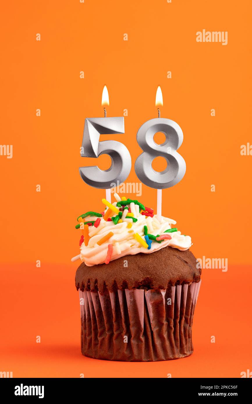Torta di compleanno con candela numero 58 - sfondo schiumoso arancione Foto Stock