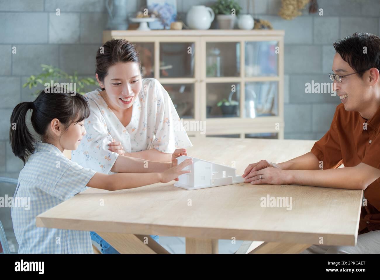 La famiglia che parla mentre guarda un modello di una casa Foto Stock