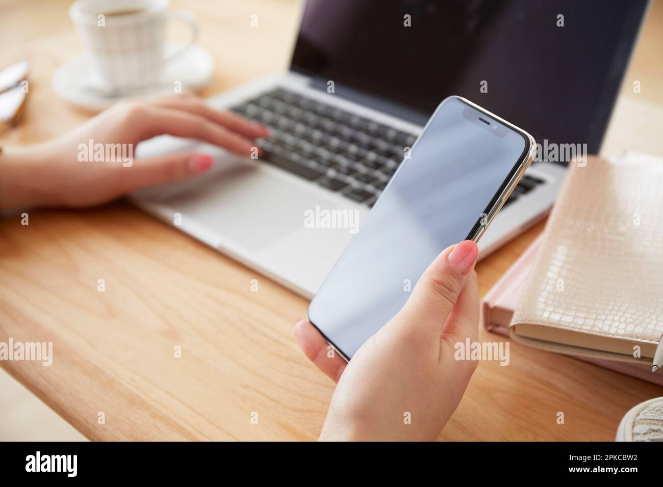 Donna con uno smartphone mentre utilizza un computer portatile Foto Stock