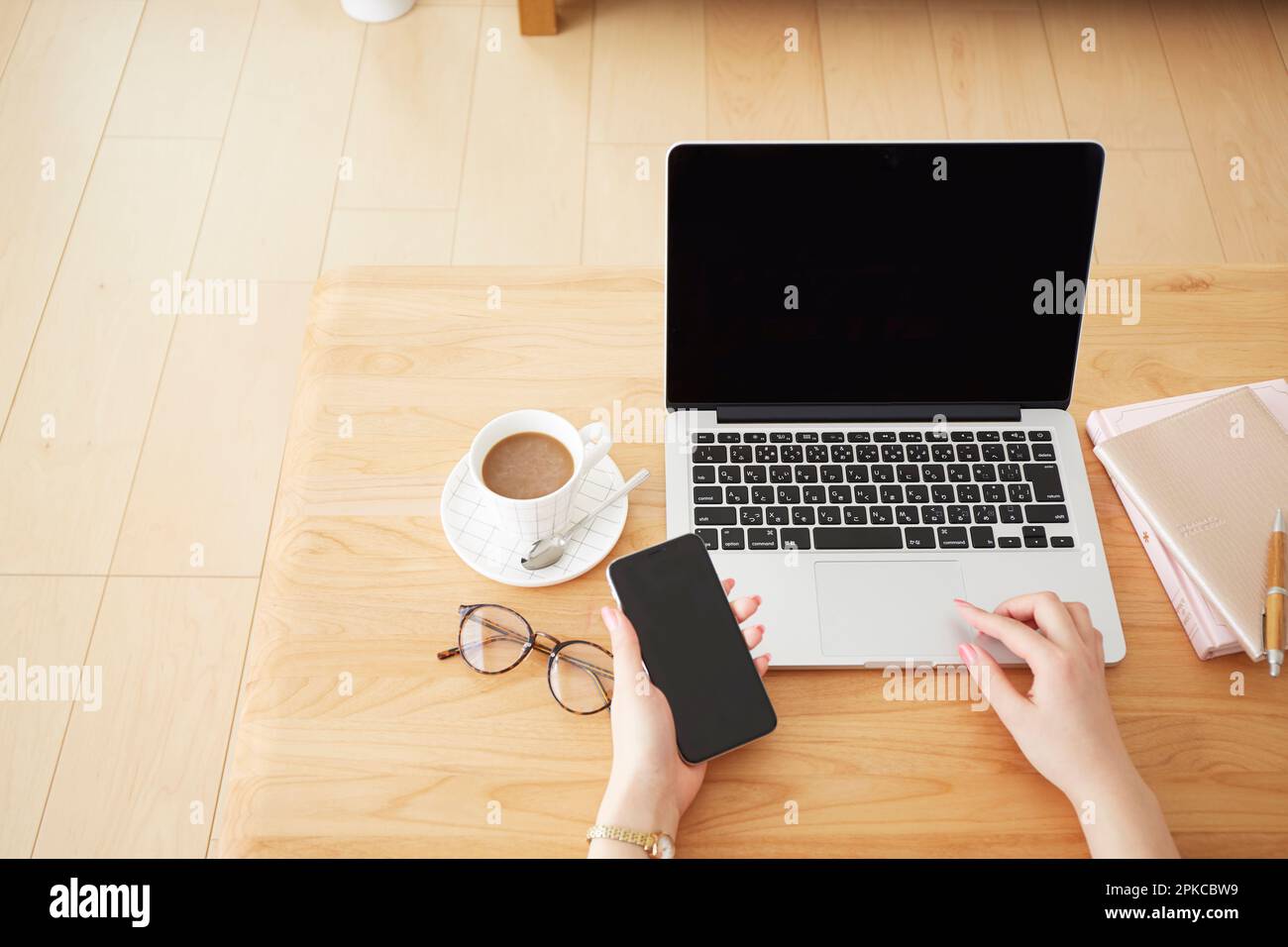 Donna con smartphone mentre utilizza un computer portatile Foto Stock