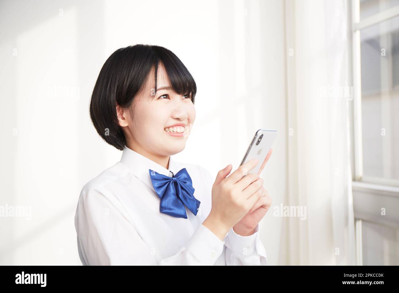 Sorridente ragazza della scuola superiore che tiene uno smartphone Foto Stock