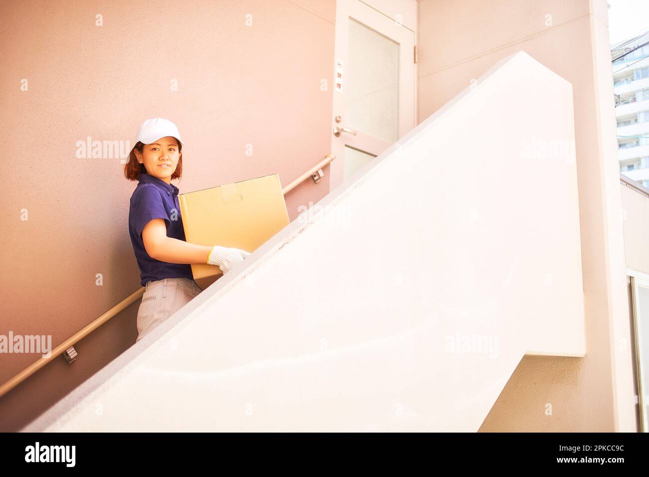 Donna in abiti da lavoro in piedi sulle scale dell'edificio dell'appartamento Foto Stock
