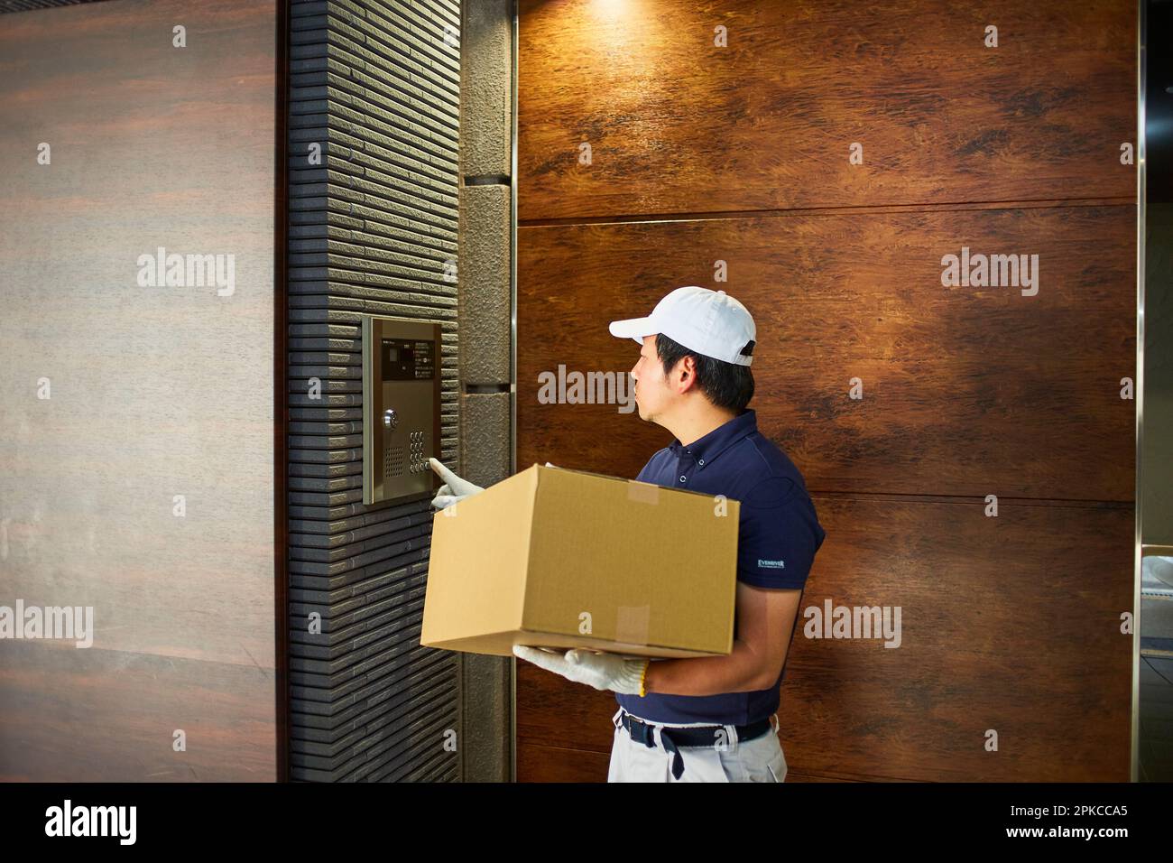 Uomo in abiti da lavoro che spinge il citofono di un appartamento Foto Stock