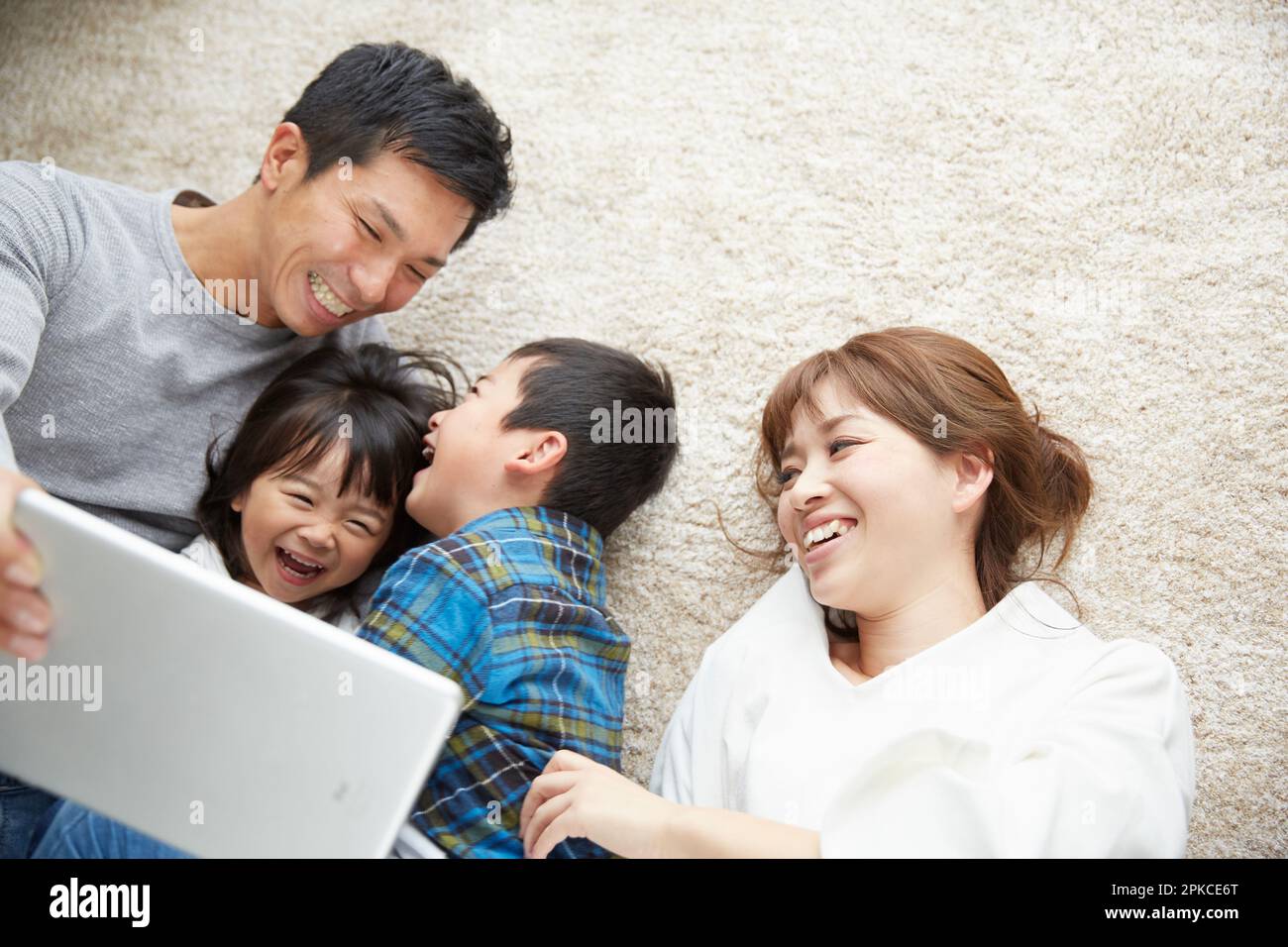 La famiglia utilizza un dispositivo tablet mentre si sdraia in salotto Foto Stock