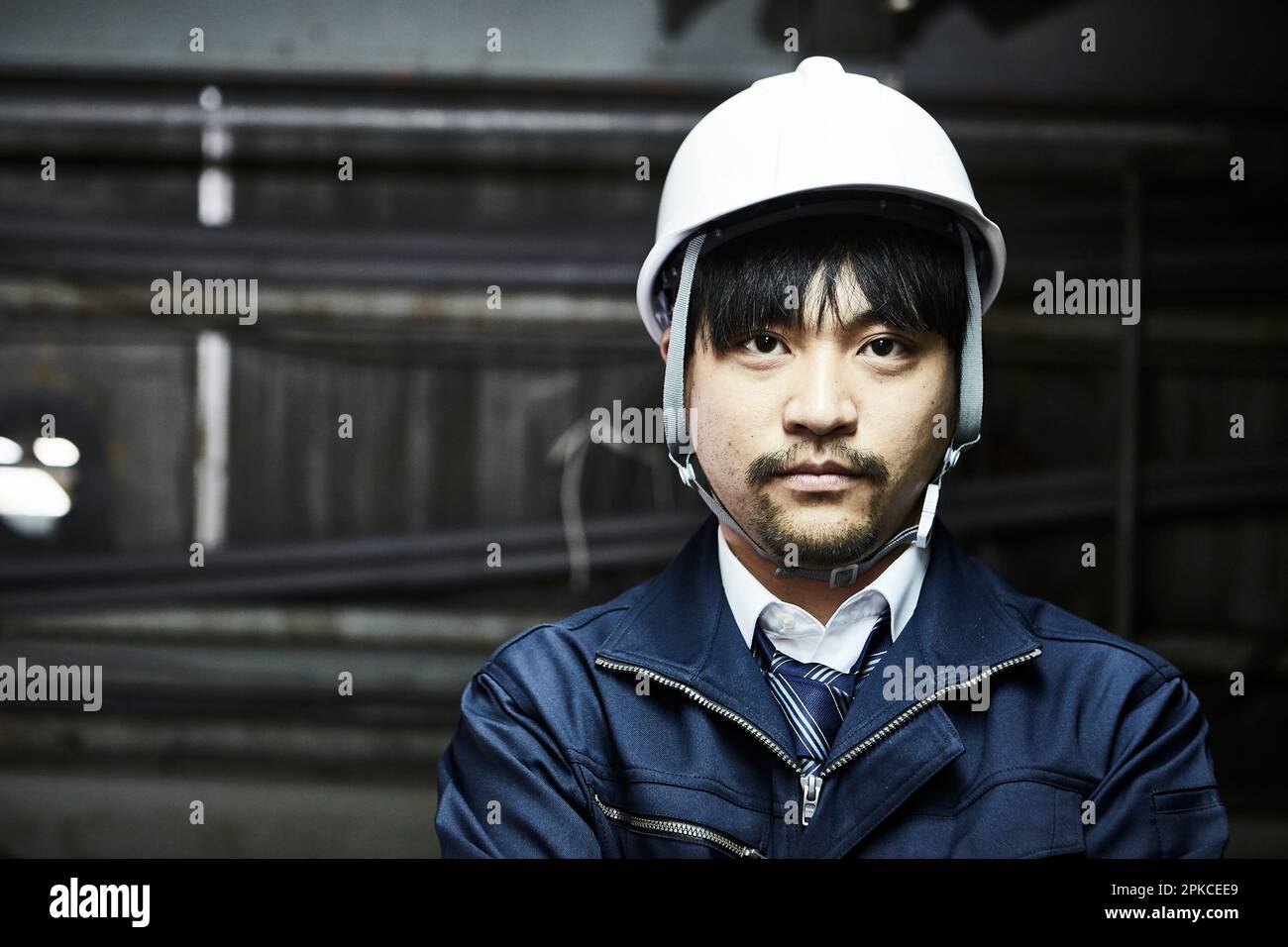 Uomo in abiti da lavoro e casco rivolto davanti Foto Stock