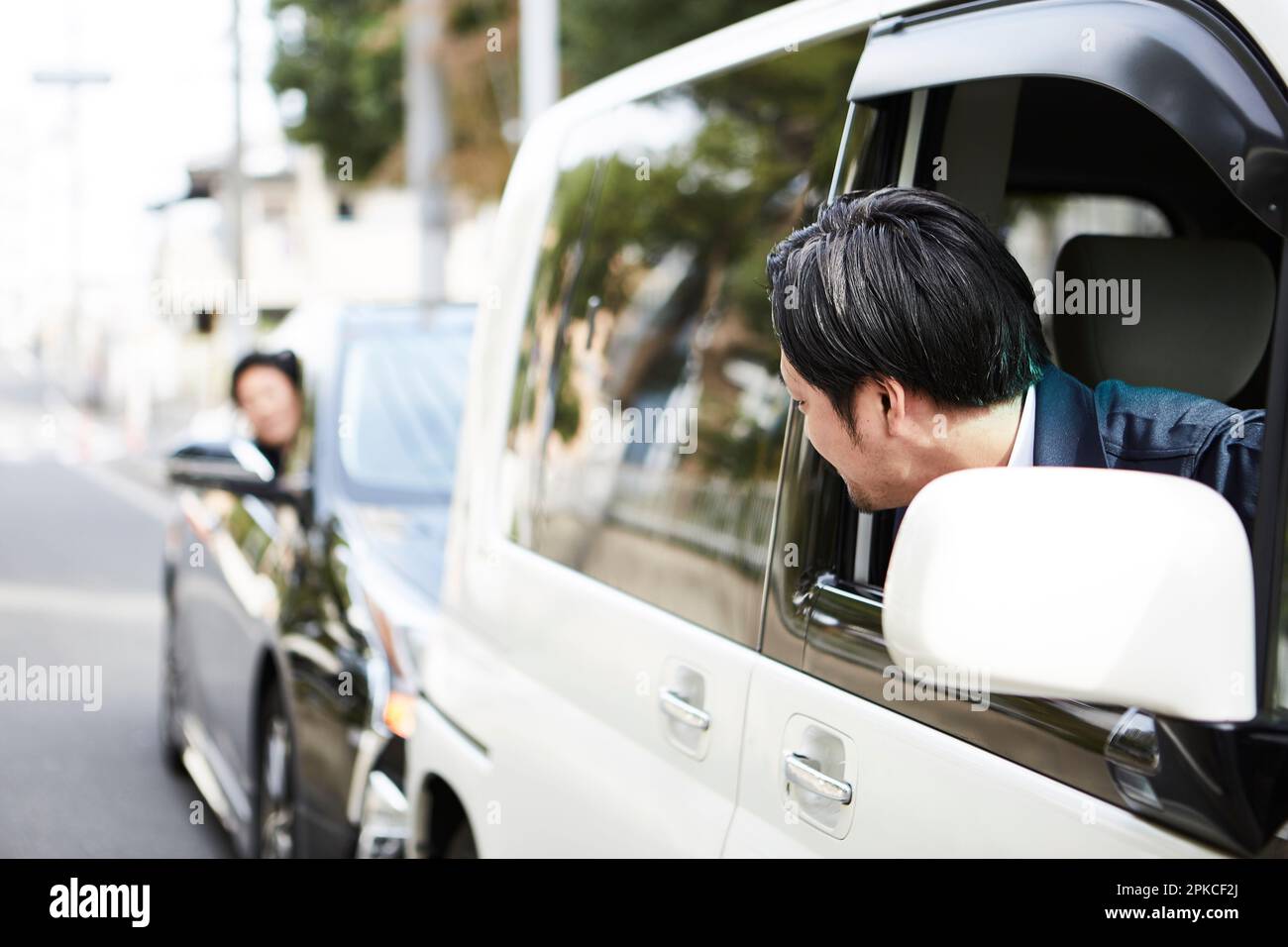 Due uomini con il volto fuori dai finestrini di due automobili Foto Stock
