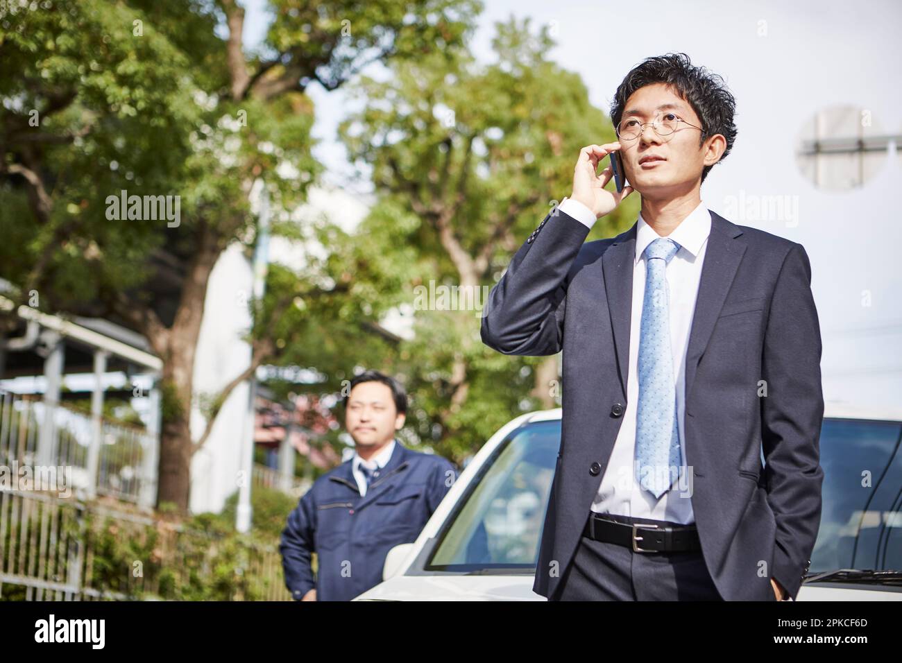 Uomo in piedi accanto all'auto e uomo che effettua una telefonata Foto Stock
