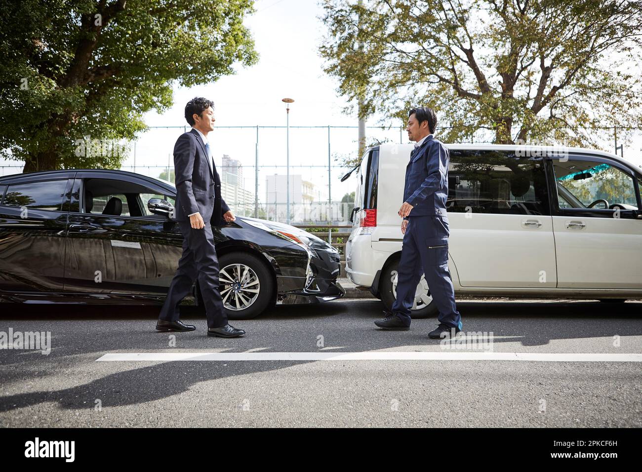 Due auto e due uomini che camminano l'uno verso l'altro Foto Stock