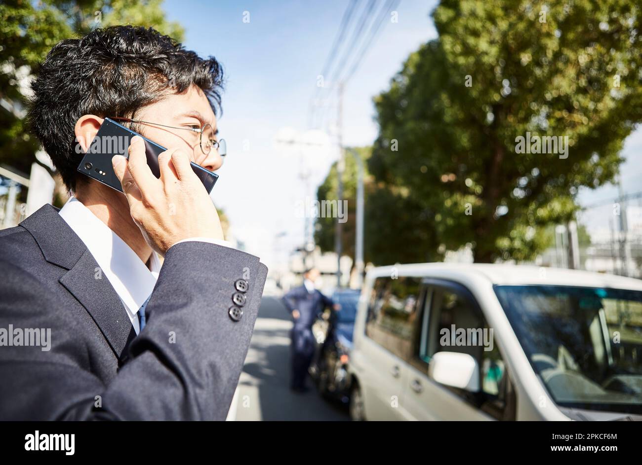 Vista laterale di un uomo che effettua una telefonata davanti a un'auto Foto Stock
