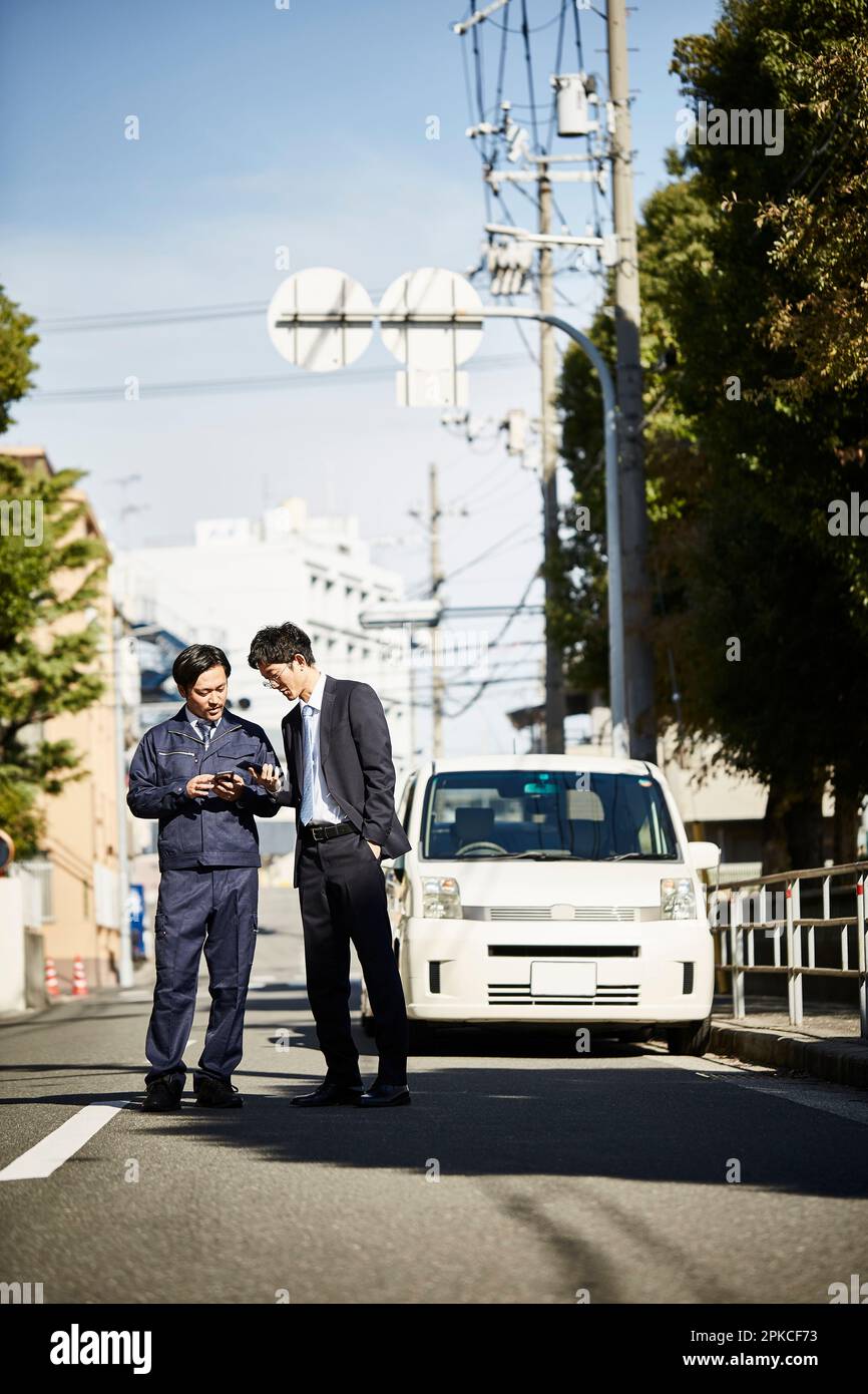 Due uomini in piedi davanti a un'auto che parla Foto Stock