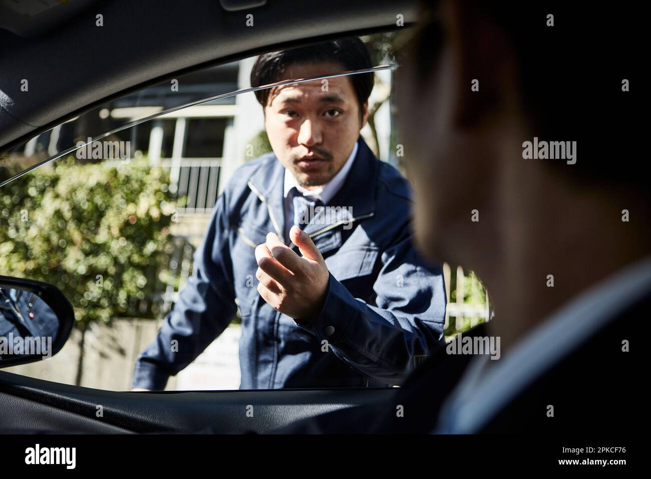 Uomo che parla con qualcuno all'interno di un'auto dall'esterno dell'auto Foto Stock
