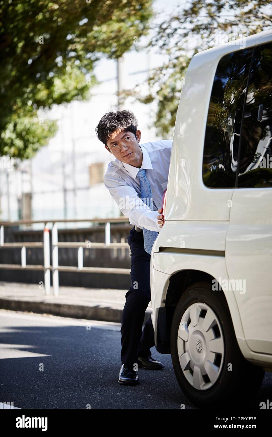 Uomo che spinge una macchina bianca Foto Stock