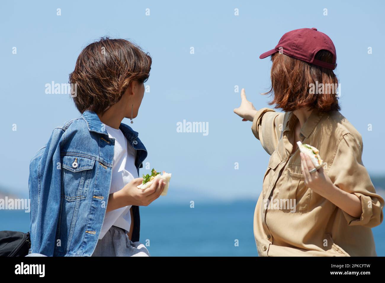 Due donne che guardano indietro e puntano in lontananza durante il pranzo Foto Stock