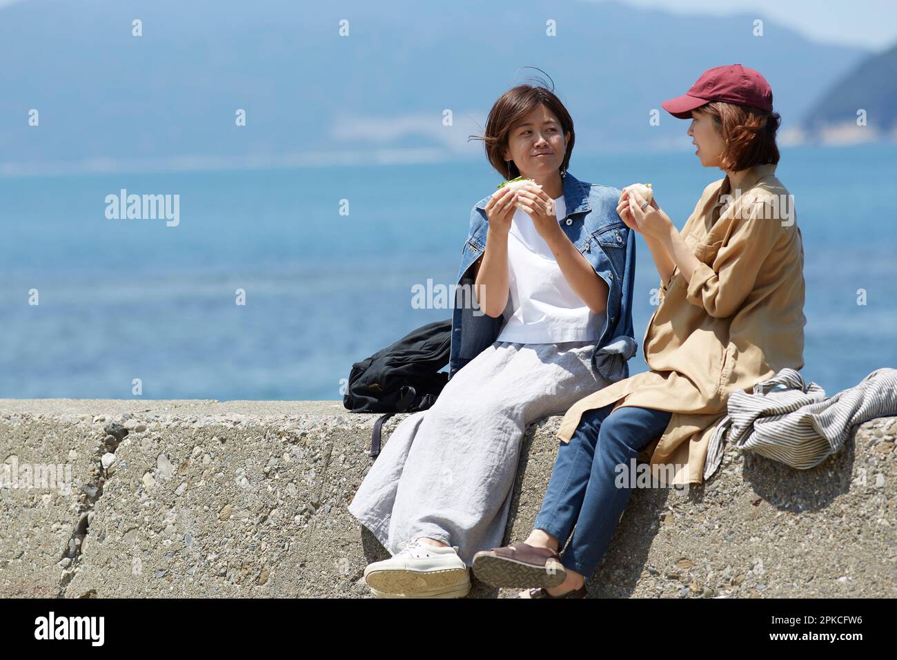 Due donne mangiano panini sul terrapieno Foto Stock