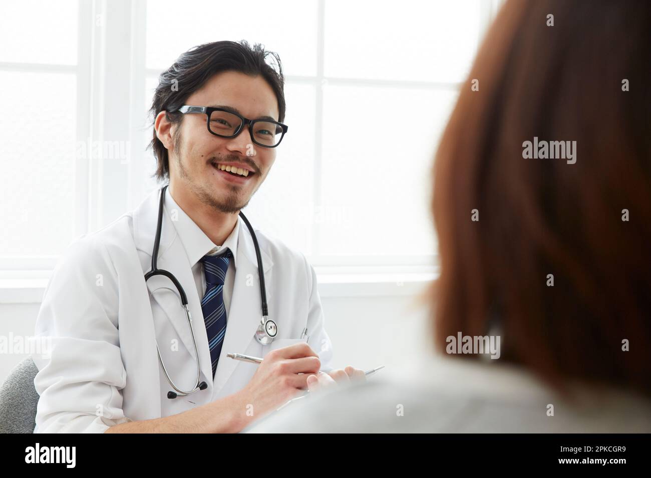 Sorridente medico di sesso maschile che fa un colloquio medico Foto Stock