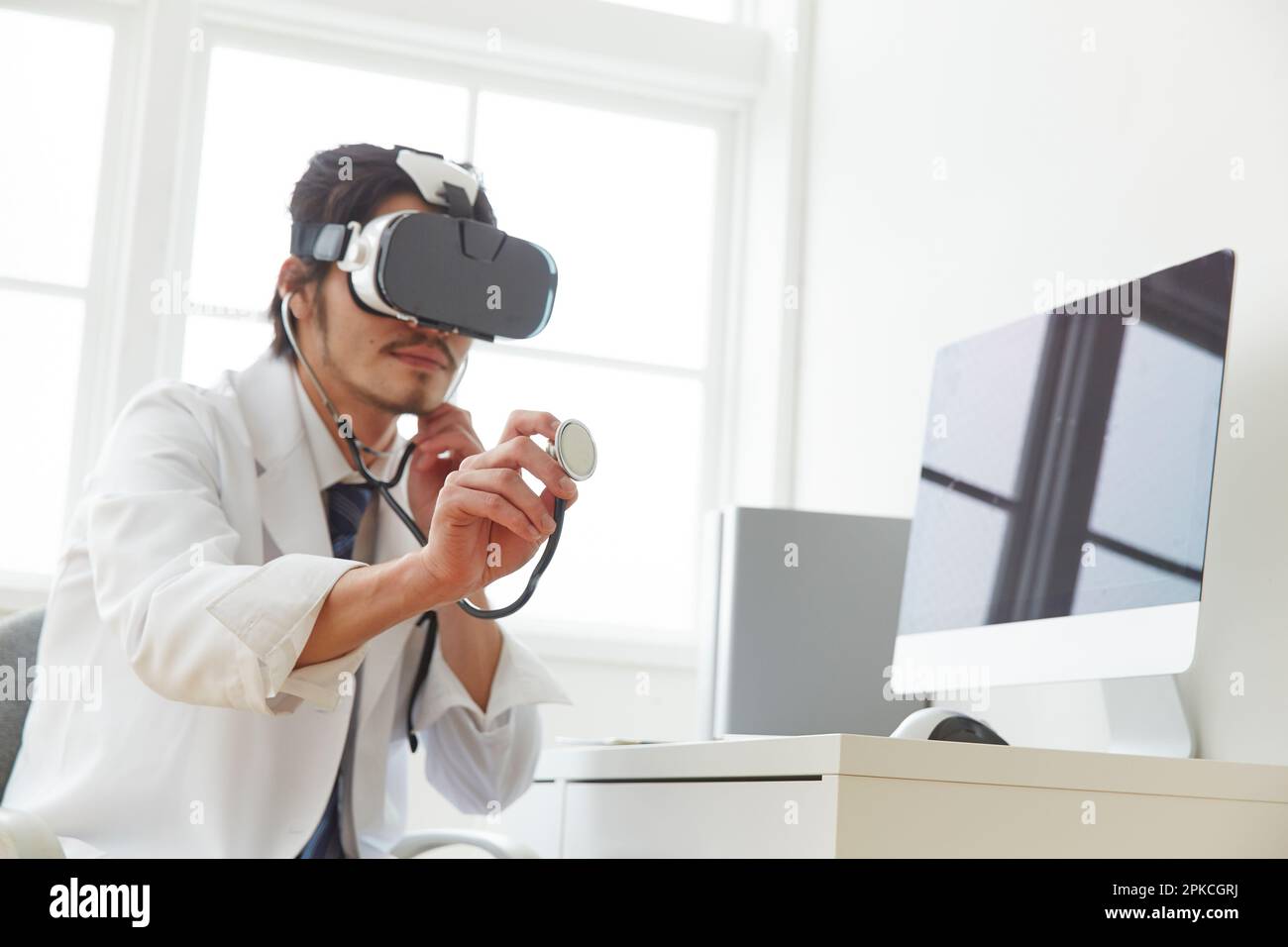 Un medico che indossa occhiali VR e applica uno stetoscopio Foto Stock