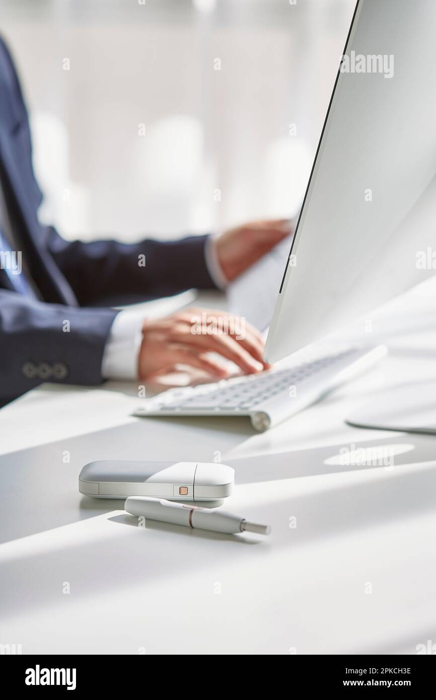 Un uomo alla sua scrivania che fuma un ICO Foto Stock